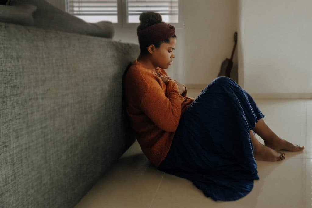 Une femme assise a sa main posée sur son coeur du fait de l'anxiété